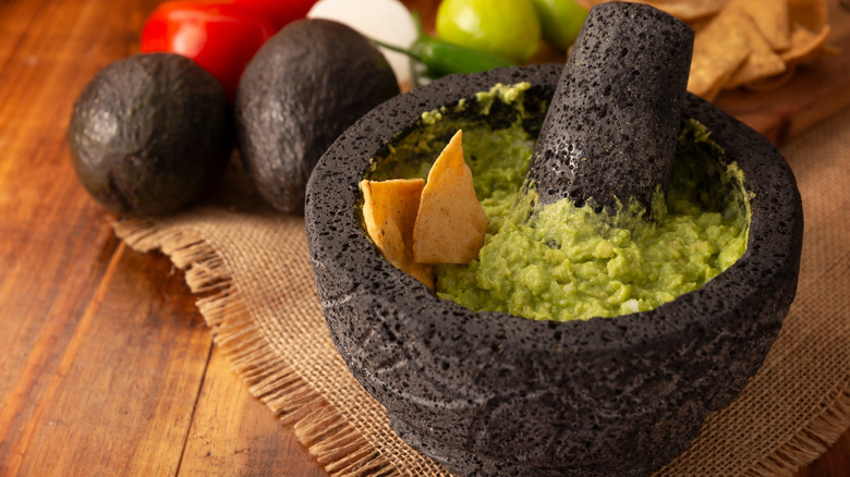 guacamole in a traditional Mexican mortar on a wood background